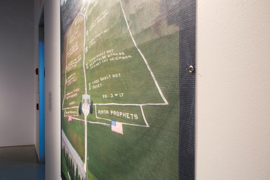 Gallery installation view featuring large-scale photographs of various courthouse buildings displayed on white walls, with polished concrete floors reflecting the artworks and benches arranged for viewers.