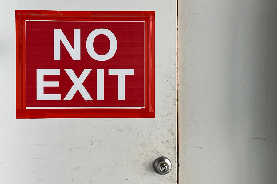 A white door with a bold red "NO EXIT" sign taped to it.