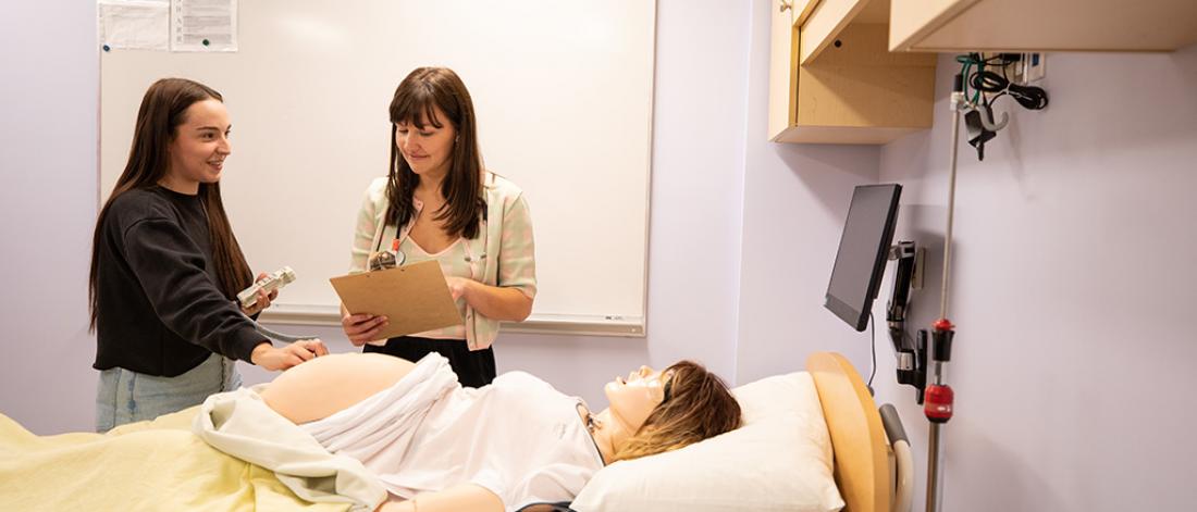 A midwifery student and instructor doing an assessment on a pregnant simulation patient