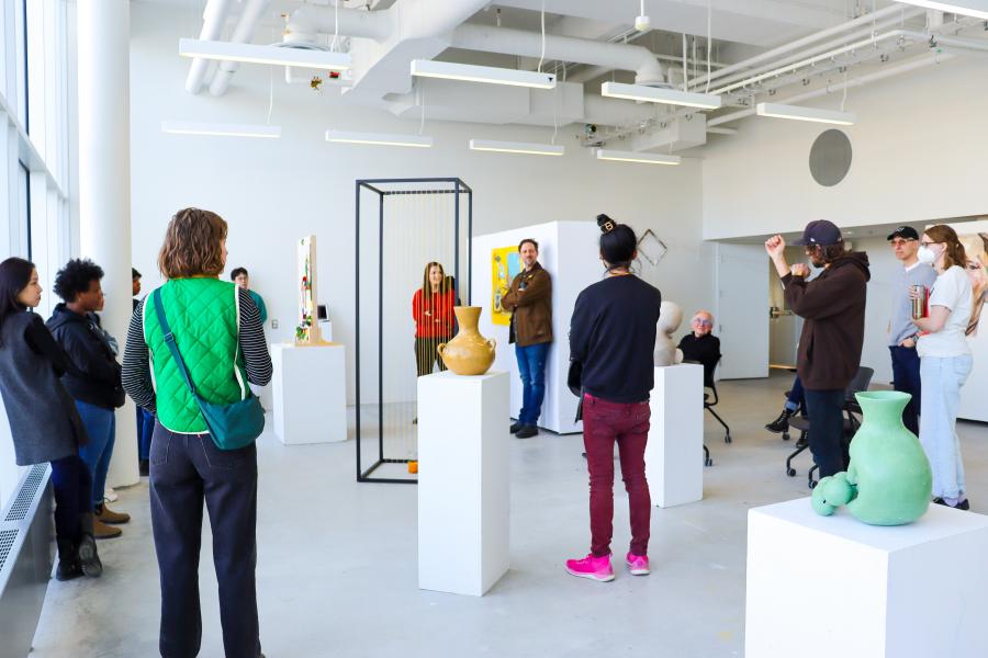 A group of student gather around an art installation in discussion