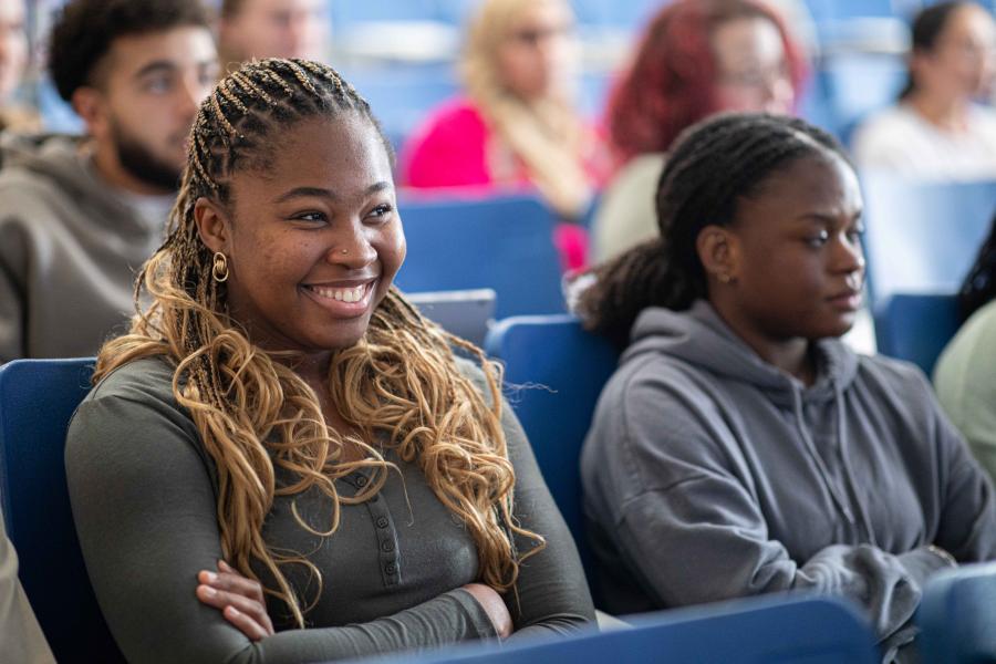 A student smiling as they listen in on a lecture.