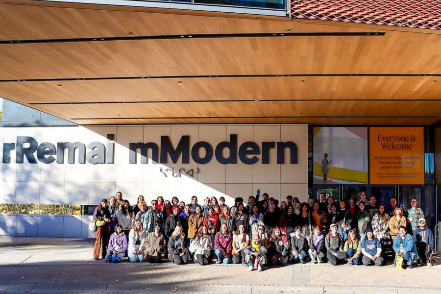 A large group poses for a photo outside the Remai Modern art museum.