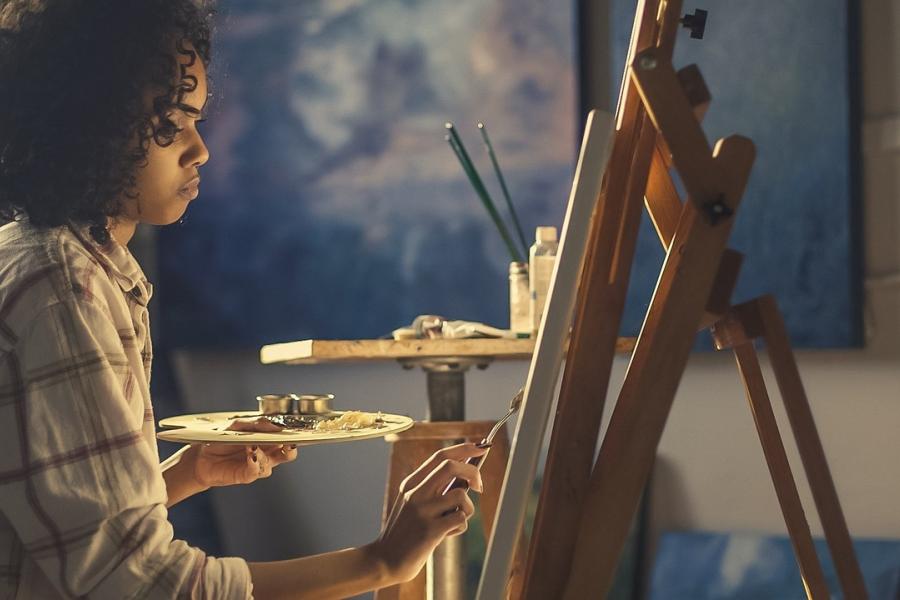 Woman painting at an easel.