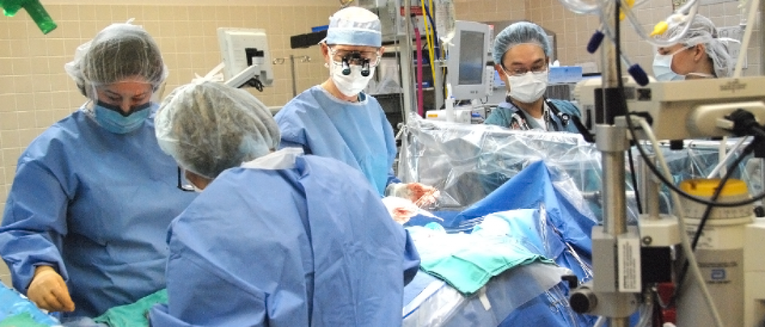 four surgeons in an operating room with a patient on the operating table.