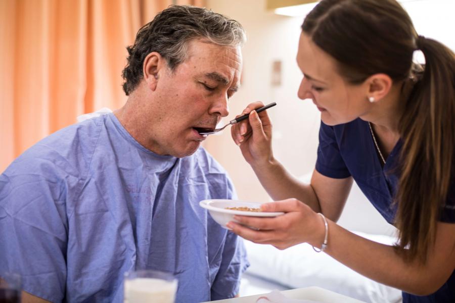 Senior being spoon-fed by a nurse.