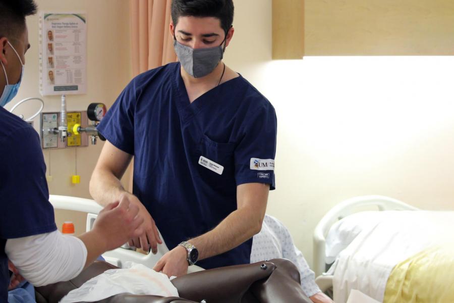 Two nursing students practice a skill with a robotic patient.